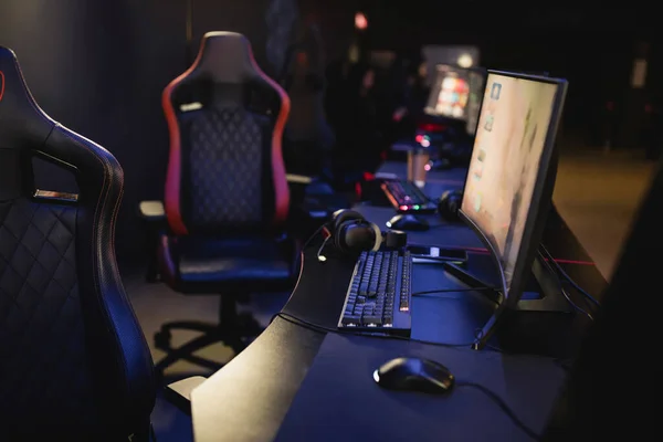 Компьютеры и игровые стулья в современном киберклубе с освещением — стоковое фото