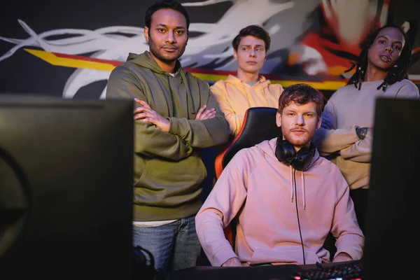 Multiethnische Gamer blicken in Spielklub auf Kamera in der Nähe von Computern — Stockfoto