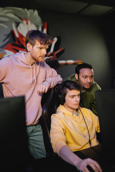 Konzentriertes multiethnisches Team beim Spielen von Videospielen am Computer im Spieleklub — Stockfoto