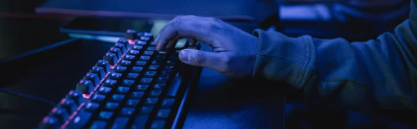 Ausgeschnittene Ansicht des Spielers mittels Tastatur im Spielclub mit blauer Beleuchtung, Banner — Stockfoto