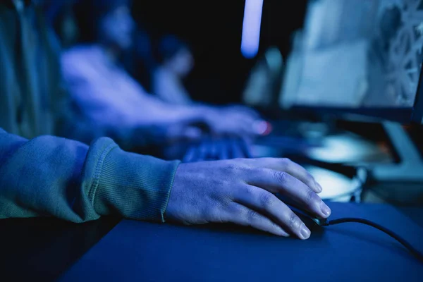 Vista recortada del jugador utilizando el ratón de la computadora mientras juega videojuego en el club de juegos - foto de stock