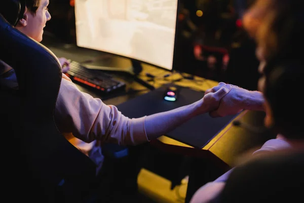 Les joueurs serrent la main tout en jouant au jeu informatique dans le cyber-club — Photo de stock