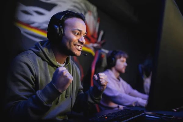 Emocionado jugador indio en los auriculares mirando el monitor de la computadora en el club de juego - foto de stock