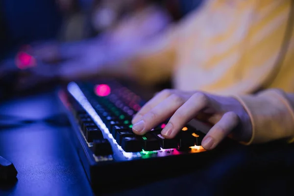 Cropped view of gamer using keyboard with lighting in cyber club — Stock Photo