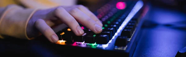 Cropped view of gamer using keyboard with lighting in gaming club, banner — Stock Photo