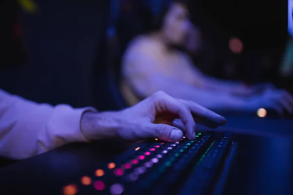 Обрезанный вид геймера с помощью клавиатуры с освещением в кибер-клубе — стоковое фото
