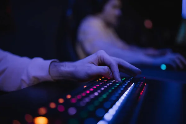 Vista cortada do jogador usando teclado com iluminação colorida no clube de jogos — Fotografia de Stock