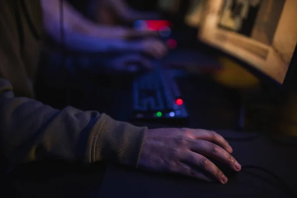 Ausgeschnittene Ansicht eines Spielers, der in der Nähe eines verschwommenen Computers im Cyber-Club sitzt — Stockfoto