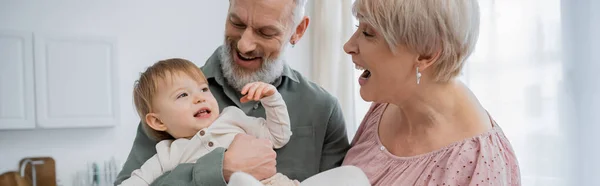 Aufgeregtes älteres Paar spielt mit Kleinkind-Enkelin zu Hause, Banner — Stockfoto