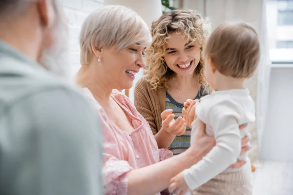 Joyful women playing with toddler child at home in living room — Stock Photo