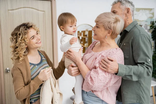 Mature couple meeting happy daughter with toddler child at home — Stock Photo