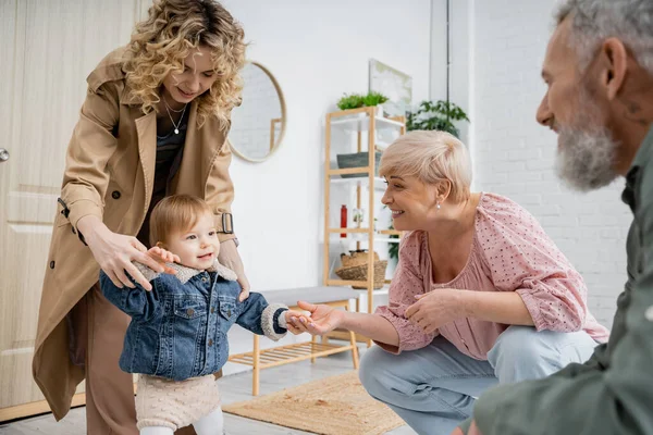 Happy middle aged woman meeting daughter with little girl in denim jacket at home — Stock Photo