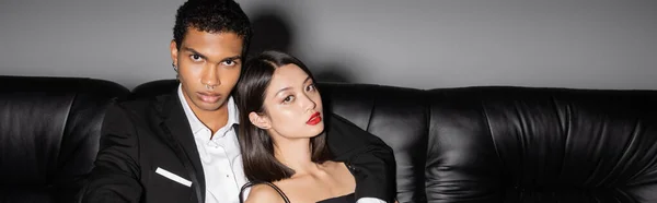 Élégant homme afro-américain embrassant femme asiatique sensuelle avec des lèvres rouges sur fond gris, bannière — Photo de stock