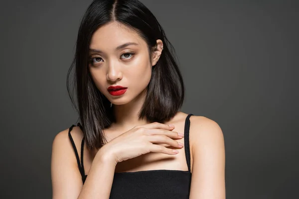 Porträt einer eleganten asiatischen Frau mit roten Lippen, die isoliert auf grau in die Kamera blickt — Stockfoto