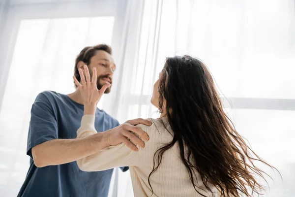 Brunette woman beating blurred boyfriend during quarrel at home — Stock Photo