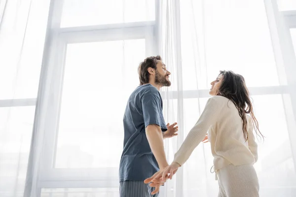 Vista de ángulo bajo de la pareja en pijama discutiendo durante la ruptura en casa - foto de stock