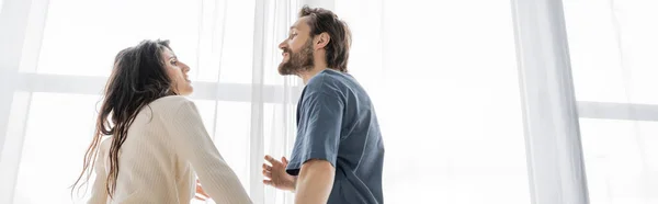 Side view of bearded man quarreling at brunette girlfriend at home, banner — Stock Photo