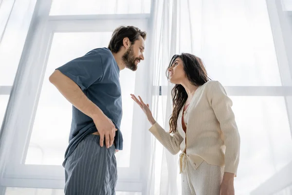 Vista de ángulo bajo de la mujer agresiva hablando con el novio durante el conflicto en casa - foto de stock