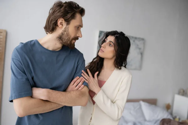Brunette woman talking to displeased boyfriend during conflict in bedroom — Stock Photo