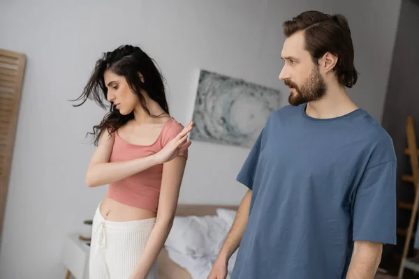 Donna sconvolta in pigiama che non mostra alcun gesto al fidanzato barbuto in camera da letto a casa — Foto stock