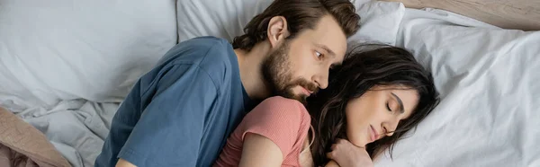 Top view of man looking at sleeping girlfriend on bed at home, banner — Stock Photo
