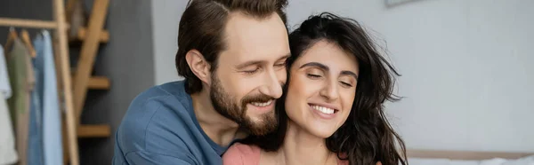 Homme barbu souriant debout près de la petite amie brune à la maison, bannière — Photo de stock