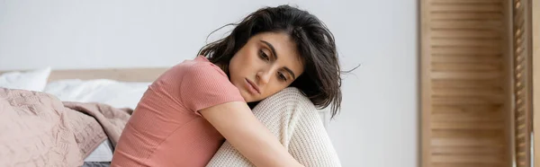 Donna bruna frustrata seduta vicino al letto a casa, striscione — Foto stock