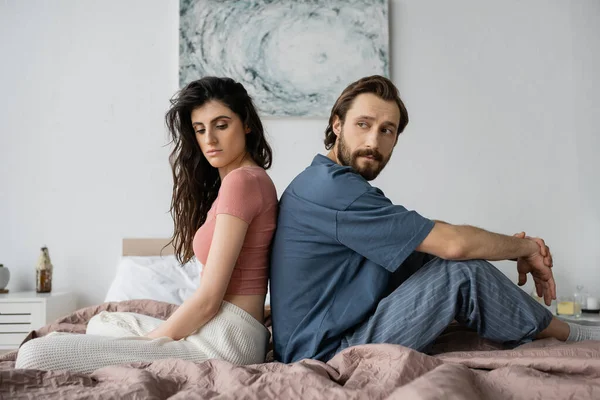 Femme bouleversée en pyjama assis dos à dos avec petit ami asexuel au lit — Photo de stock