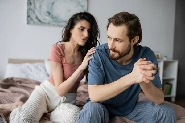Brunette woman calming down boyfriend with clenched hands in bedroom — Stock Photo