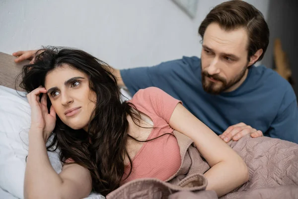 Verschwommener Mann schaut brünette Freundin an, die zu Hause auf Bett liegt — Stockfoto