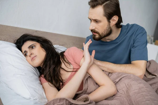 Асексуальная женщина показывает стоп-жест бойфренду, когда лежит дома на кровати — стоковое фото