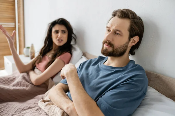 Gleichgültiger Mann schaut weg, während wütende Freundin sich im Schlafzimmer streitet — Stockfoto
