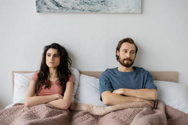 Пара з труднощами у відносинах, що перетинають руки, сидячи на ліжку вдома — стокове фото
