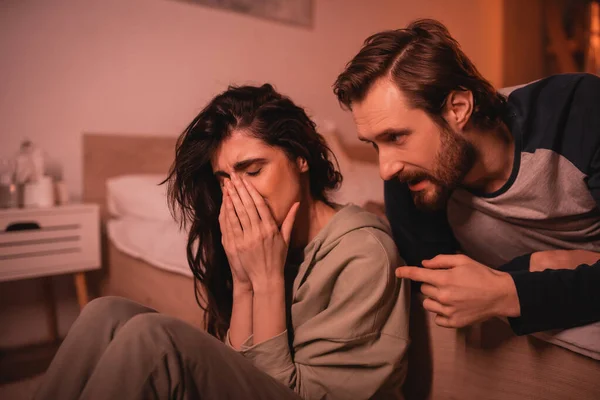 Homem barbudo brigando em choro namorada no quarto à noite — Fotografia de Stock