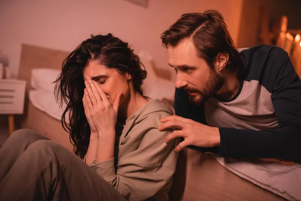 Piangere donna ricevendo cura dal fidanzato barbuto in camera da letto in serata — Foto stock