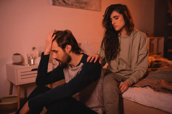 Femme brune attentionnée apaisant triste petit ami dans la chambre le soir — Photo de stock