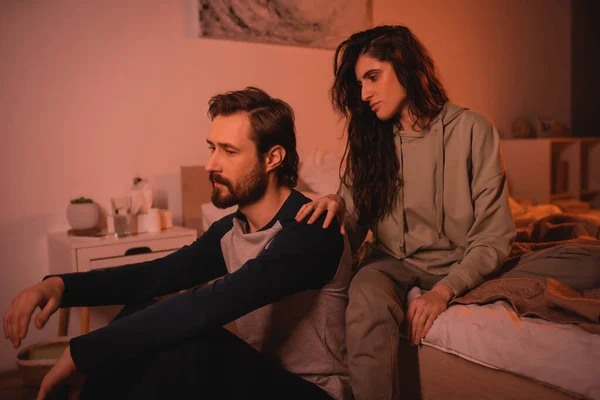 Caring woman touching shoulder of upset boyfriend in bedroom at home — Stock Photo