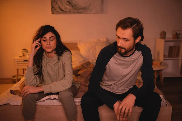 Displeased couple with relationship crisis sitting on bed at home in evening — Stock Photo