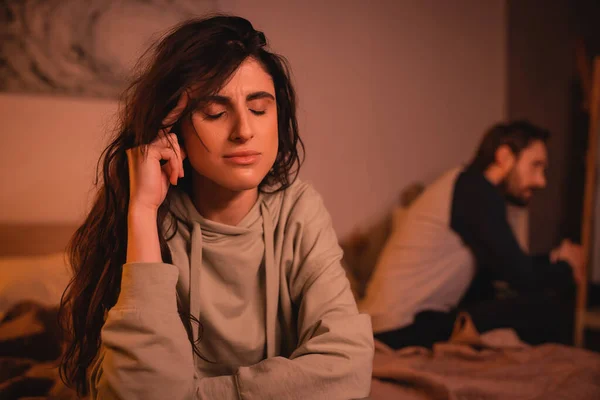 Displeased woman sitting near blurred boyfriend on bed at home — Stock Photo
