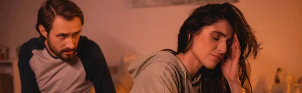 Displeased woman sitting near blurred boyfriend talking at home in evening, banner — Stock Photo