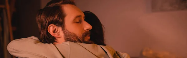 Mujer abrazando novio barbudo en casa por la noche, pancarta - foto de stock