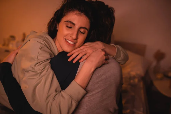 Carefree woman hugging boyfriend in bedroom in evening — Stock Photo