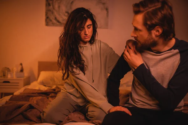 Brunette woman calming down boyfriend on bed in evening — Stock Photo