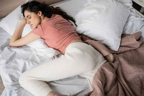 Vue grand angle de la femme brune dormant sur le lit le matin — Photo de stock