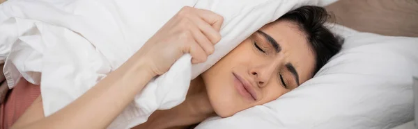Femme mécontente mettant oreiller sur la tête sur le lit le matin, bannière — Photo de stock