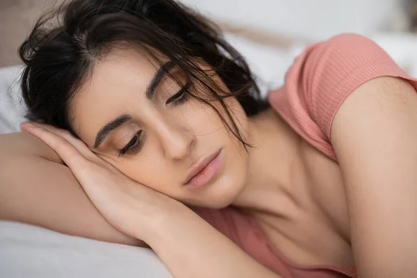 Portrait of sad brunette woman lying on bed at home — Stock Photo