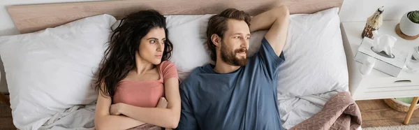 Vista dall'alto della donna insoddisfatta che incrocia le braccia vicino al fidanzato sul letto al mattino, banner — Foto stock