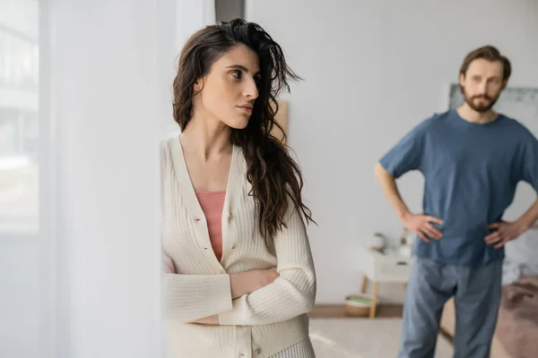 Оскорбленная женщина, стоящая у занавеса во время ссоры с парнем дома — стоковое фото