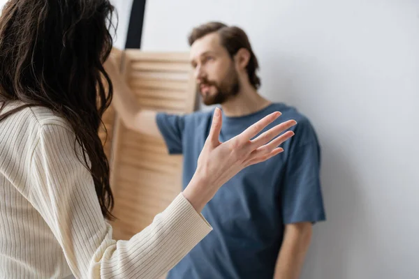 Brunette woman quarrelling with blurred boyfriend at home — Stock Photo