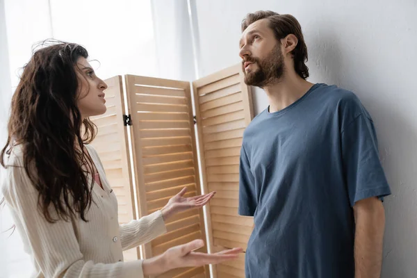Mulher irritada conversando com namorado pensativo durante dificuldades de relacionamento em casa — Fotografia de Stock